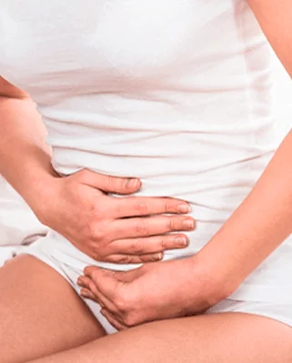 Pessoa com as mãos sobre a parte inferior do abdome, região abordada na cirurgia colorretal